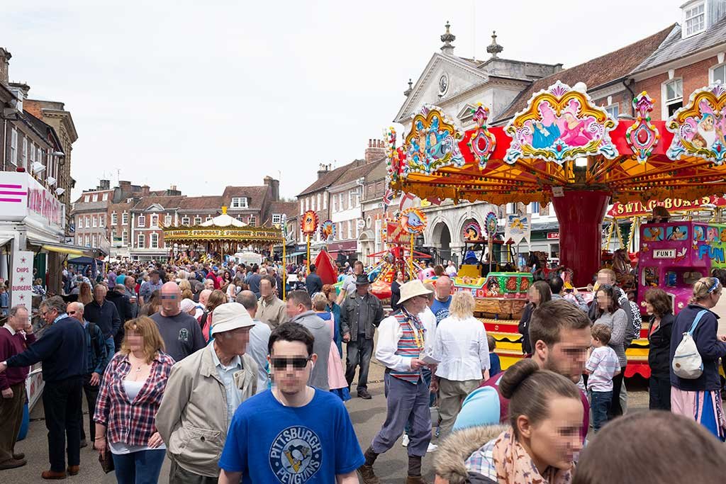 Blandford Market Place full of fairground rides, market stalls and visitors